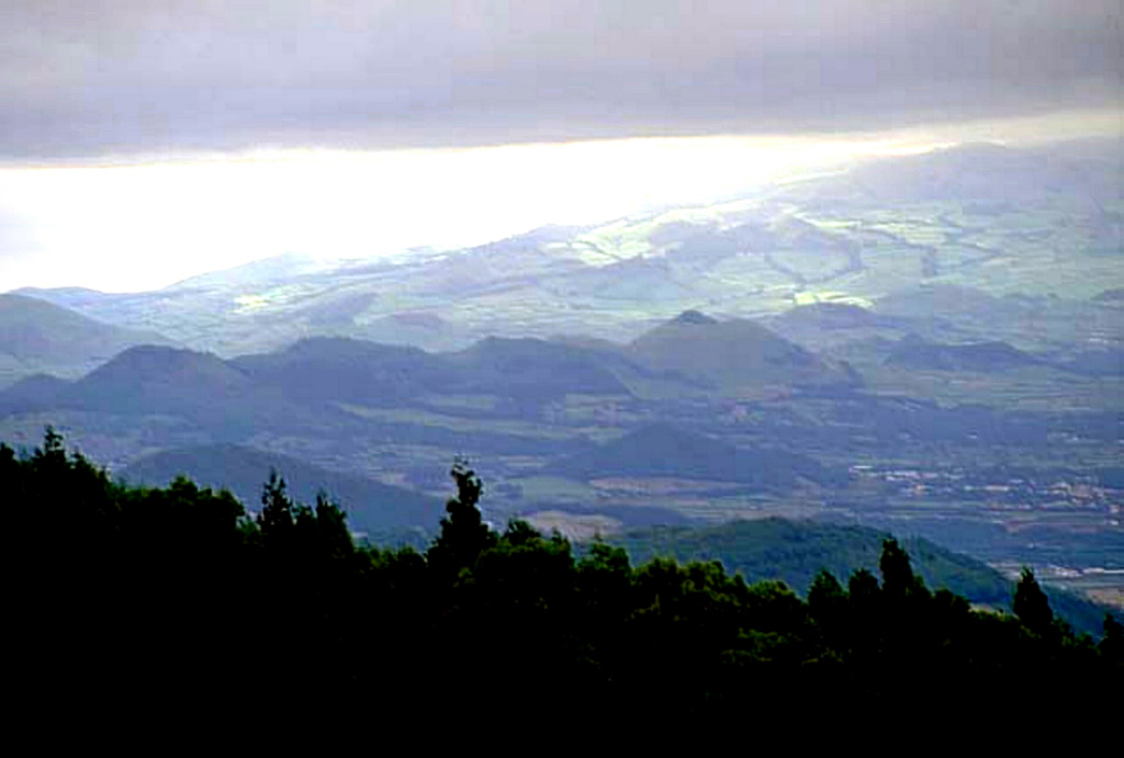 A chain of scoria cones known as the Picos Fissural Volcanic System encompasses Sao Miguel Island between Sete Cidades and Agua de Pau volcanoes, seen in this view from the east below the Agua de Pau (Lagoa do Fogo) caldera. Scoria cones are the dominant volcanic form in the system, and over 270 are recognized here. The southern coast of Sao Miguel appears in the background. About 30 eruptions have occurred during the past 5,000 years, including eruptions in 1563 and 1652. Copyrighted photo by Marco Fulle, 2000 (Stromboli On-Line, http://stromboli.net).