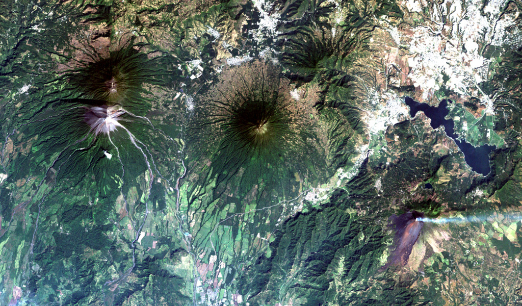 Guatemala's capital city (upper right) is flanked by four major stratovolcanoes and a large caldera.  Steaming Pacaya volcano (lower right) was constructed near the southern rim of the partially lake-filled Amatitlán caldera, whose major late-Pleistocene silicic eruptions have produced thick pyroclastic-flow deposits exposed around Guatemala City.  Conical Agua volcano (center) is a prominent landmark from the city, and the paired volcanoes of Acatenango and Fuego (left) lie to the west. NASA Landsat image, 2000 (courtesy of Loren Siebert, University of Akron).