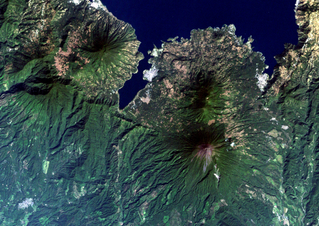 The 6-km-long, dagger-like Santiago Bay on Lake Atitlán is constrained by lava flows from San Pedro (upper left) and Tolimán (right-center) volcanoes.  Young lava flows entering the lake, in particular those from Tolimán, have created a very irregular shoreline.  The unvegetated summit of Atitlán volcano, the youngest post-caldera stratovolcano, lies south of Tolimán.  Part of the southern margin of the Atitlán III caldera, which lies below the summit of Atitlán volcano, is offset along faults just south of the tip of Santiago Bay. NASA Landsat image, 2000 (courtesy of Loren Siebert, University of Akron).