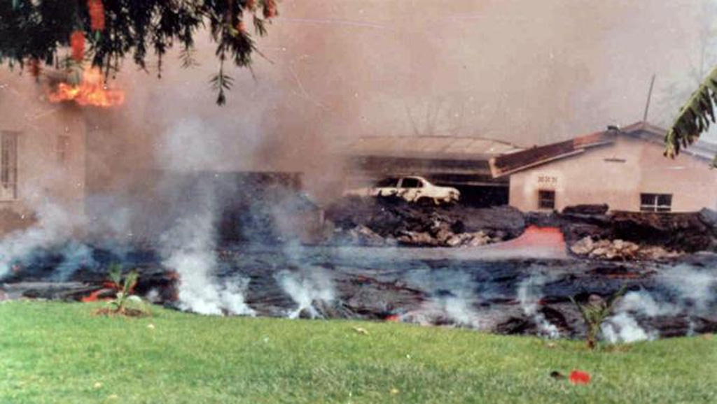 A major effusive eruption from vents on the S flank of Nyiragongo volcano in the Democratic Republic of Congo on 17-18 January 2002 produced lava flows that partially inundated the city of Goma, flowing through city streets before entering into Lake Kivu. This photo shows some of the thin and fast lava flows pouring through a narrow chute (behind the car and in line with the left-most opening in the low wall). An incandescent channel is visible at the right, and gas and steam rise from the advancing front of the lava in the foreground. Photo by Wafula, 2005.