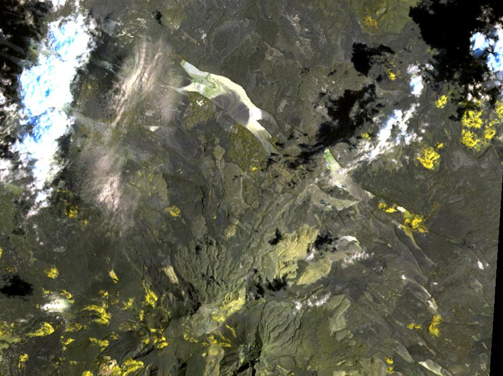 The yellow-colored pyroclastic cones at the upper right lie along the western part of the Gufa volcanic field, which extends from the Djibouti border into Eritrea (upper right). These basaltic scoria cones and lava flows are aligned in an E-W direction NE of Mousa Alli volcano, a large stratovolcano that is visible at the bottom center of this NASA Landsat image. A second E-W-trending chain of cones, not visible in this image, is located to the north of the principal chain in Eritrea and fed long lava flows that descend in the direction of the Red Sea. NASA Landsat image, 1999 (courtesy of Hawaii Synergy Project, Univ. of Hawaii Institute of Geophysics & Planetology).