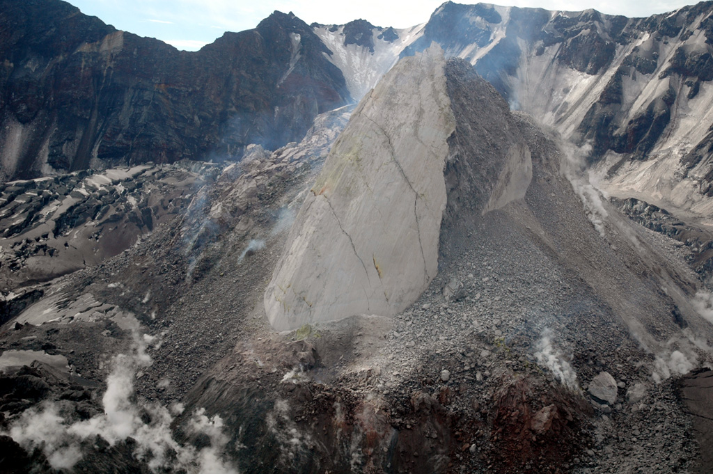 Moderate explosive eruptions beginning in October 2004 at Mount St. Helens were followed by the extrusion of a lava dome. This 21 June 2005 view from the NW shows the new dome with the 1980 crater wall in the background. The smooth-surfaced part of the dome, known informally as the Whaleback, formed by slow extrusion of viscous lava. The rougher surface to the right formed when portions of the dome collapsed, forming a talus slope. The crevassed, ash-covered surface of an uplifted glacier is visible to the left. Photo courtesy of U.S. Geological Survey, Cascades Volcano Observatory.