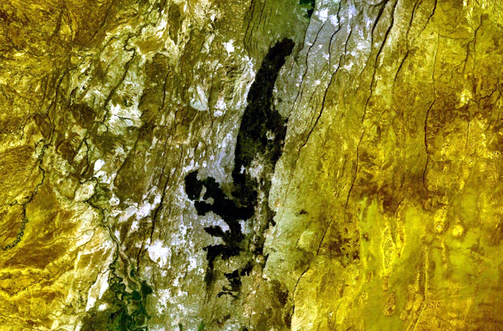 The dark-colored area cutting across the center of this NASA Landsat image (with north to the top) is a series of basaltic lava flows erupted from fissure vents at Hertali. These flows lie at the S end of the Awash Plain, about 50 km NNE of Dofen volcano. The youthful morphology of the flows suggests a late Pleistocene to Holocene age. Numerous NNE-SSW-trending fissures of the Ethiopian Rift are visible. NASA Landsat 7 image (worldwind.arc.nasa.gov)