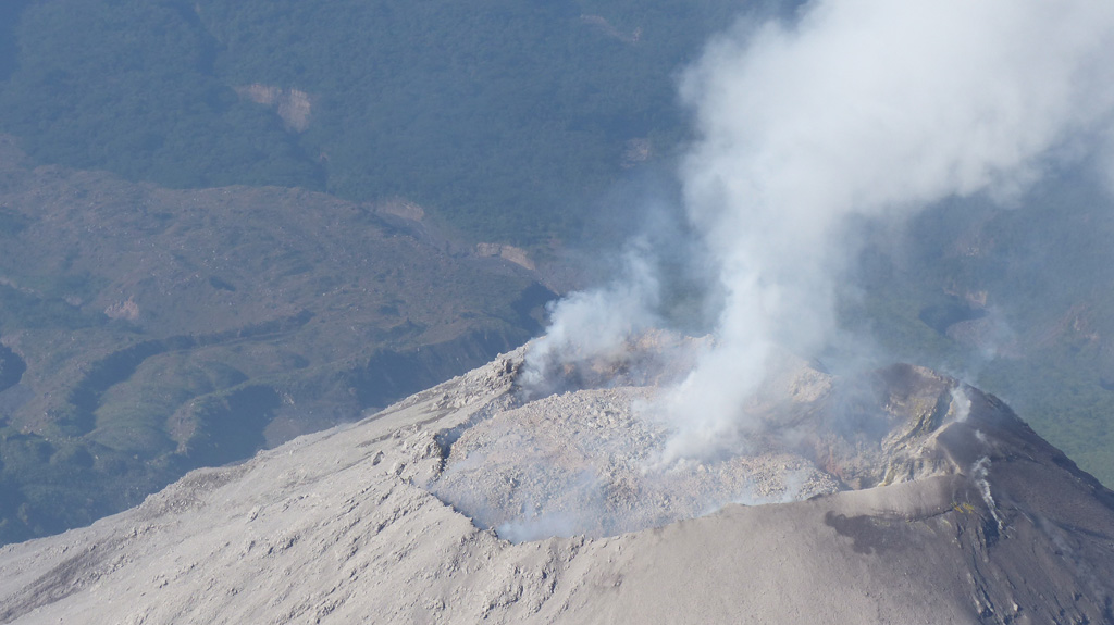 This 28 February 2017 photograph of El Caliente dome summit shows that the dome had nearly filled the crater. Pyroclastic flows from El Caliente are often caused by the partial collapse of an overflowing dome. Weak degassing is visible from the center and perimeter of the dome. Blocky lava flows produced from El Caliente vent are visible in the background. Photo by Ailsa Naismith, 2017.