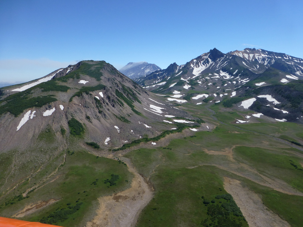 Dzenzursky is an extensively eroded, largely Pleistocene edifice in Kamchatka. Zhupanovsky is to the E, seen in the background emitting a gas plume towards the left. Photo by Janine Krippner, 2014.